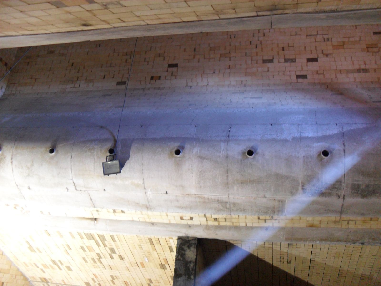 Muro de ladrillo y concreto refractario con aberturas en un equipo industrial